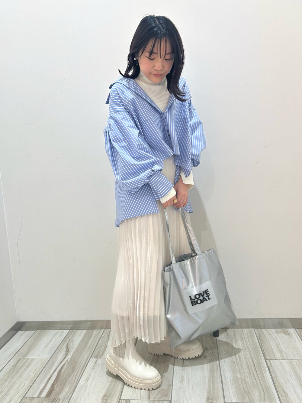 ホワイト系のブーツ、シルバー系のトートバッグ、ホワイト系のスカートを着用したレディースの冬コーディネートの2枚目の写真