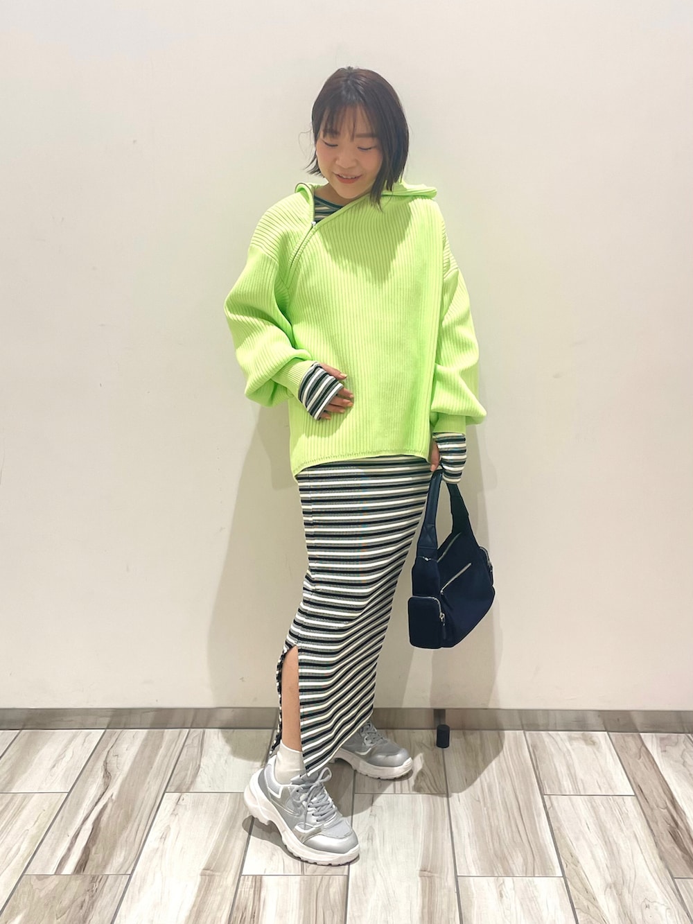 グリーン系のニット/セーター、ブラック系のワンピース、ブルー系のハンドバッグを着用したレディースの春コーディネートの2枚目の写真