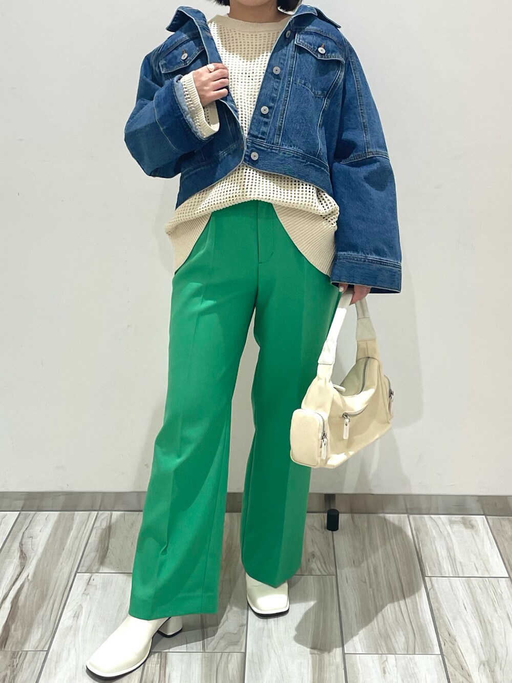 シルバー系のショルダーバッグ、グリーン系のスラックス、ホワイト系のニット/セーターを着用したレディースの春コーディネートの2枚目の写真