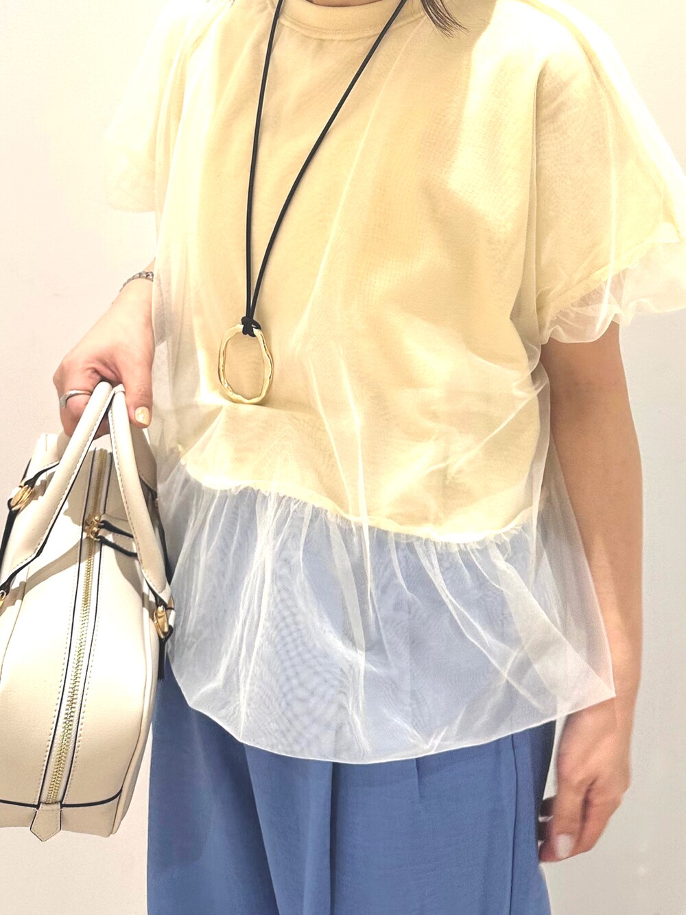 ホワイト系のボストンバッグ、ブルー系のスラックス、ホワイト系のTシャツ/カットソーを着用したレディースの春コーディネートの3枚目の写真