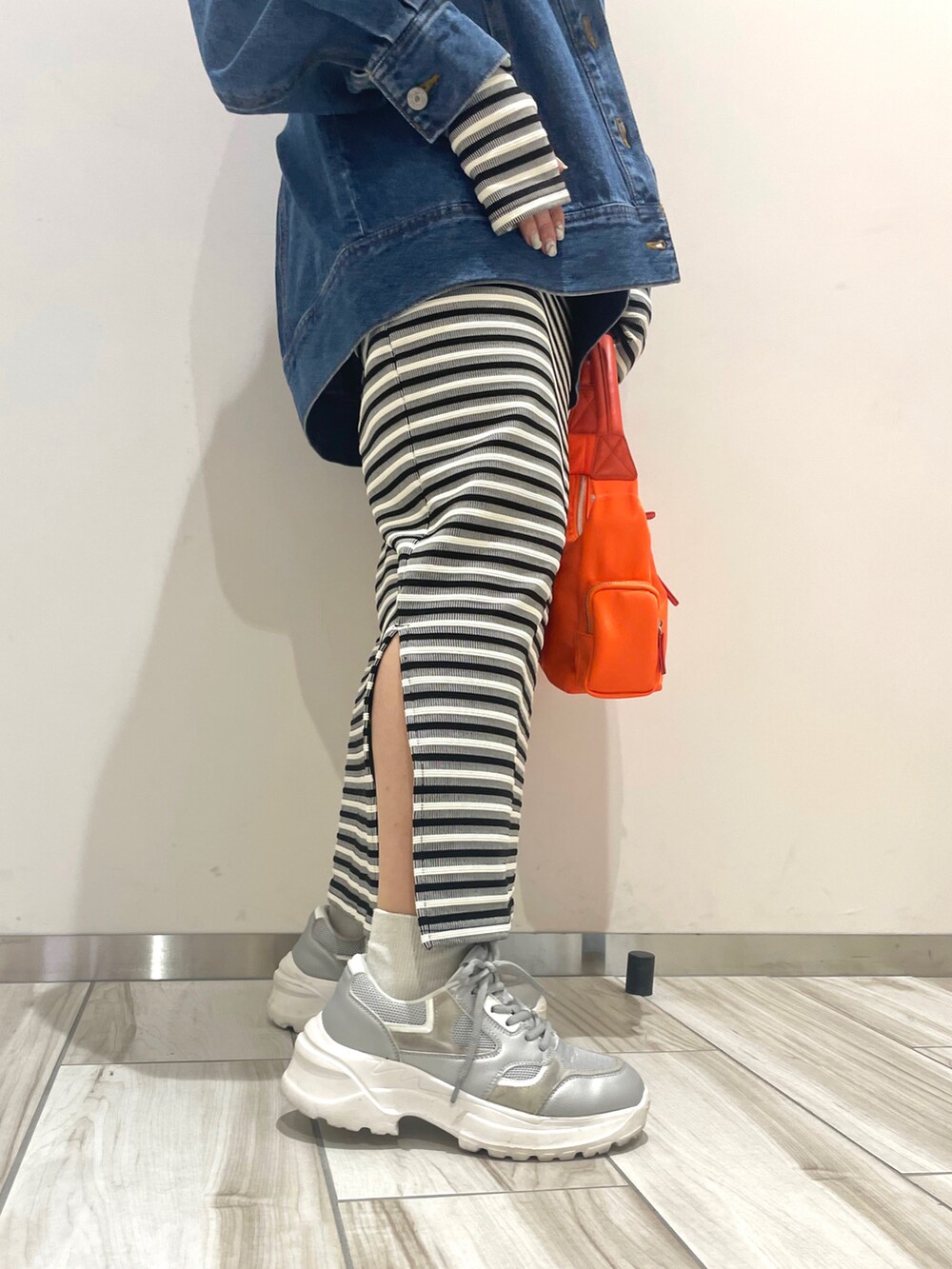 オレンジ系のハンドバッグ、ブラック系のワンピース、ブルー系のデニムジャケットを着用したレディースの春コーディネートの5枚目の写真