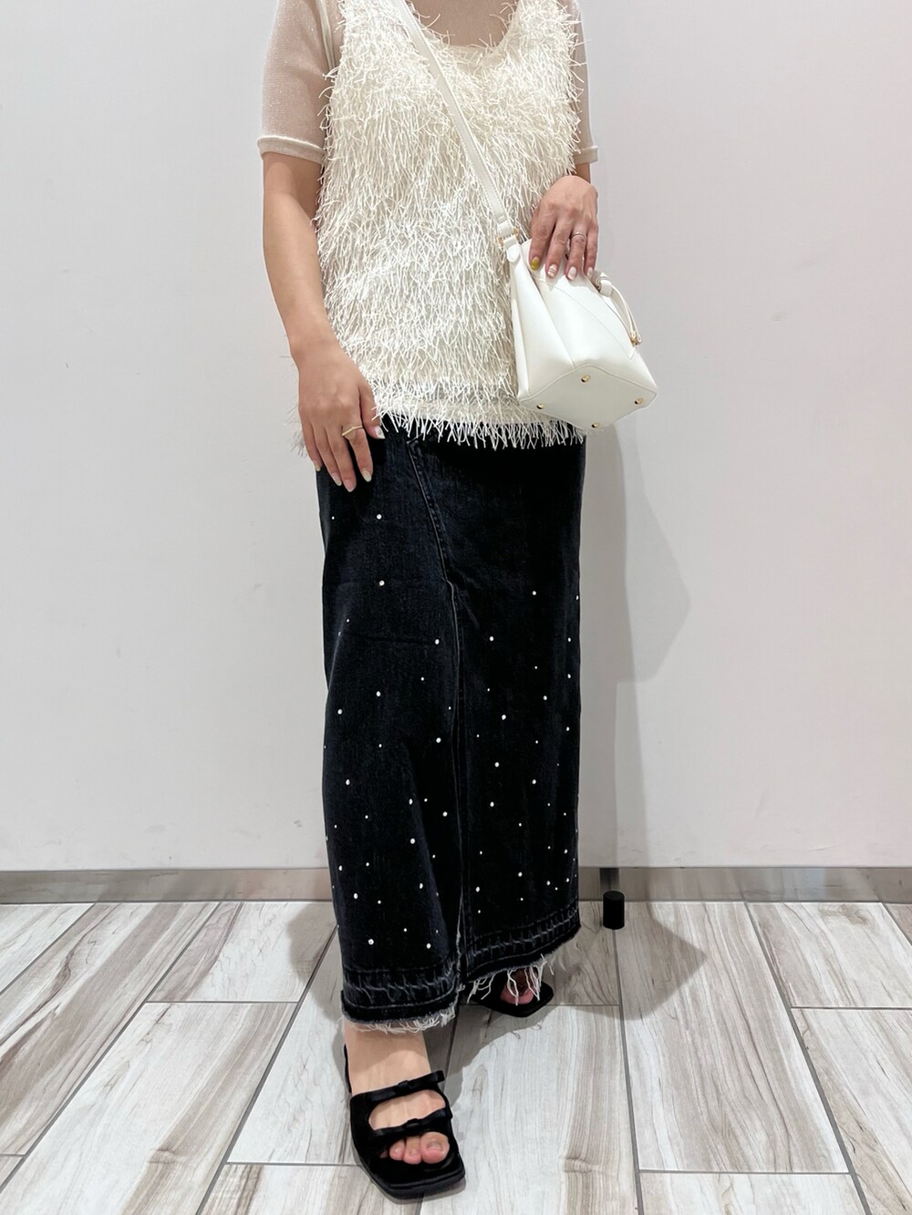 グレー系のタンクトップ、ブラック系のデニムスカート、ホワイト系のショルダーバッグを着用したレディースの夏コーディネートの5枚目の写真