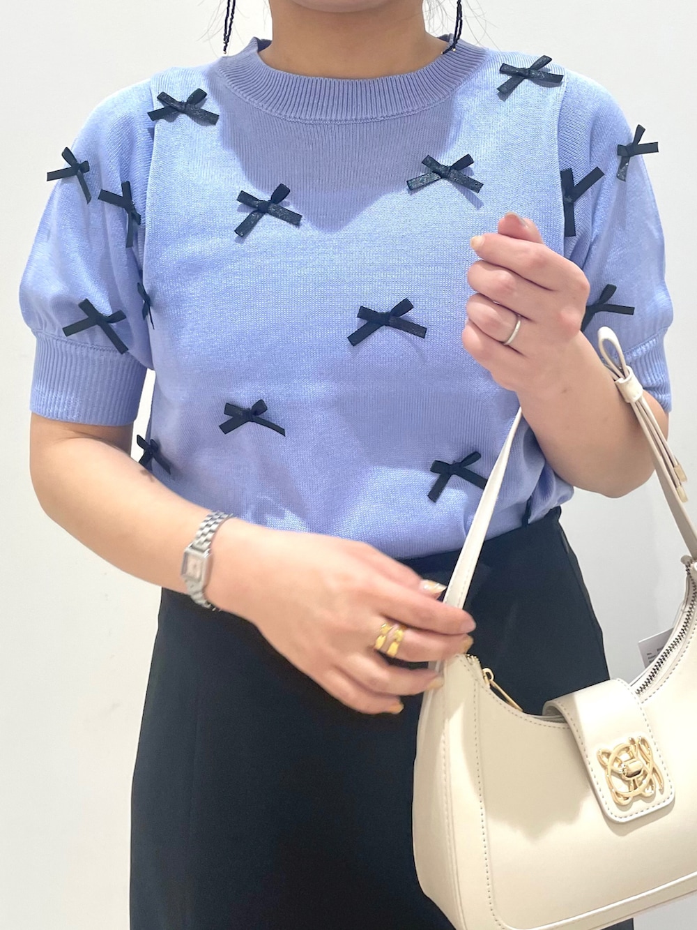 ブルー系のニット/セーター、ホワイト系のハンドバッグを着用したレディースの春コーディネートの3枚目の写真