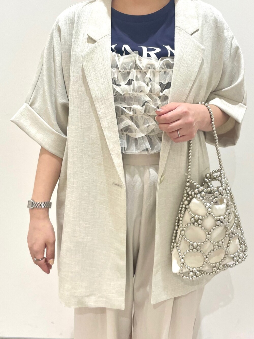 ホワイト系のテーラードジャケット、ベージュ系のその他パンツ、シルバー系のハンドバッグを着用したレディースの春コーディネートの2枚目の写真