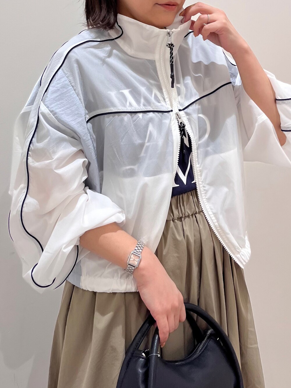 ホワイト系のブルゾン、グリーン系のスカート、ブラック系のショルダーバッグを着用したレディースの春コーディネートの2枚目の写真