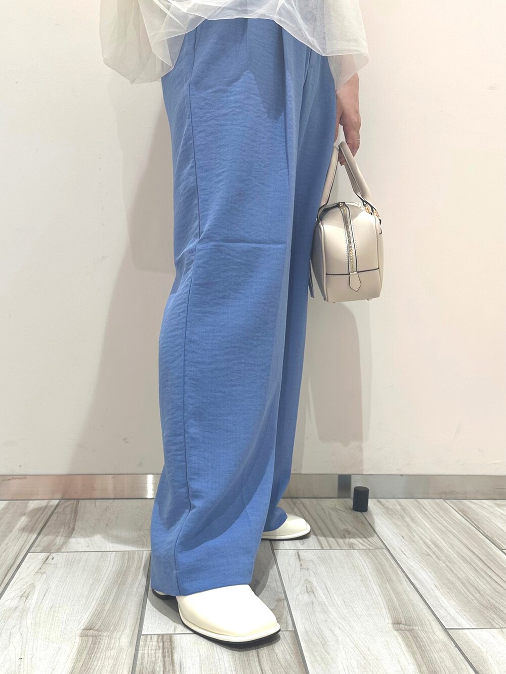 ホワイト系のボストンバッグ、ブルー系のスラックス、ホワイト系のTシャツ/カットソーを着用したレディースの春コーディネートの2枚目の写真