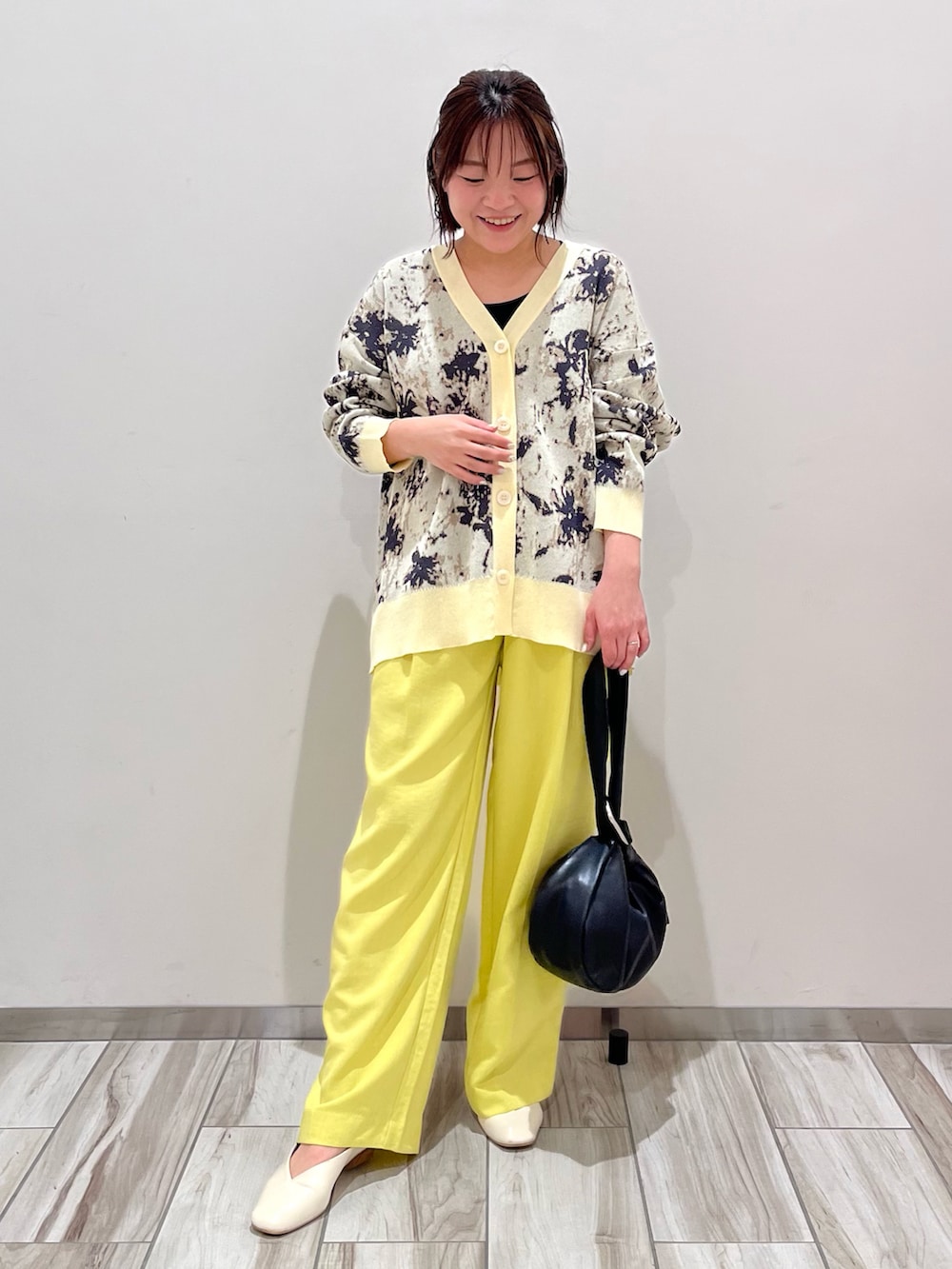 ベージュ系のカーディガン/ボレロ、イエロー系のスラックス、ブラック系のハンドバッグを着用したレディースの春コーディネートの2枚目の写真