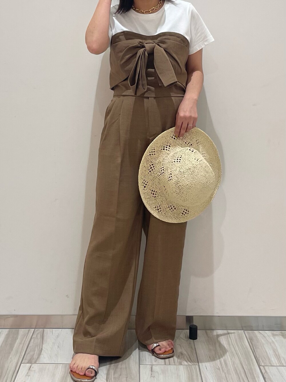 ブラウン系のスラックスを着用したレディースの夏コーディネートの2枚目の写真