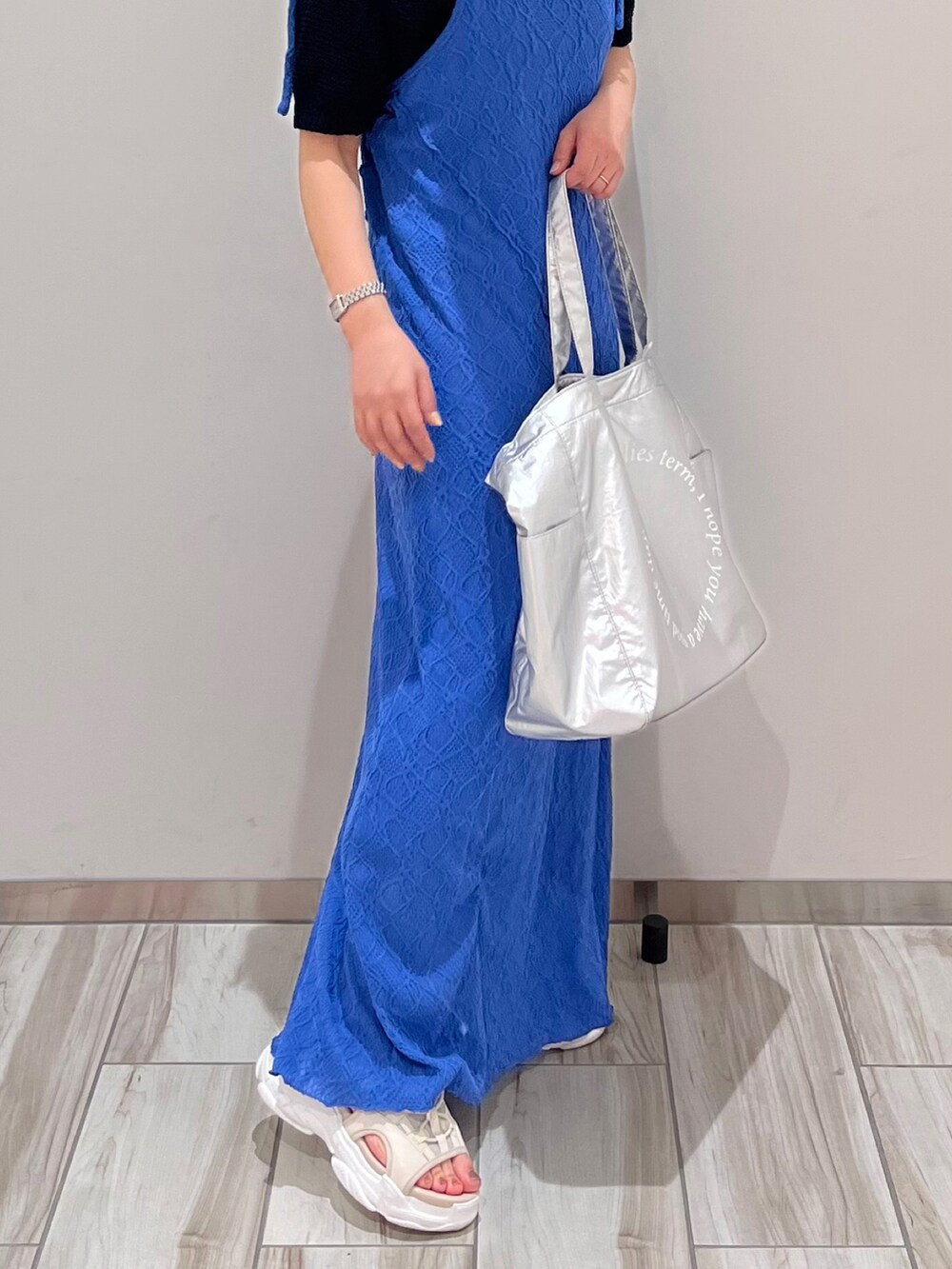 ブルー系のワンピース、シルバー系のトートバッグ、ブラック系のニット/セーターを着用したレディースの春コーディネートの3枚目の写真