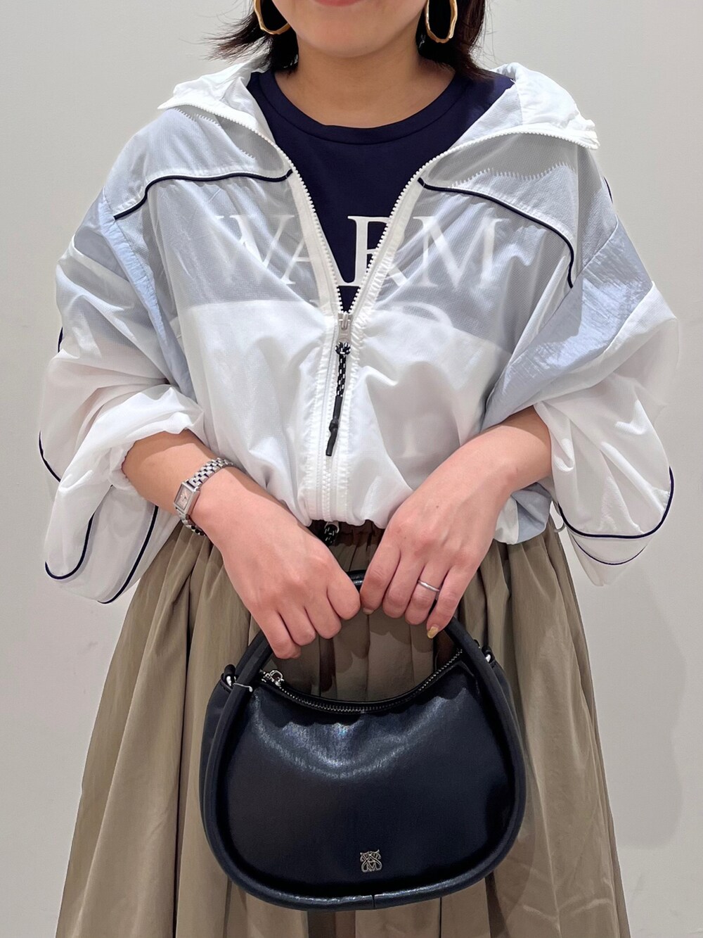 ホワイト系のブルゾン、グリーン系のスカート、ブラック系のショルダーバッグを着用したレディースの春コーディネートの3枚目の写真