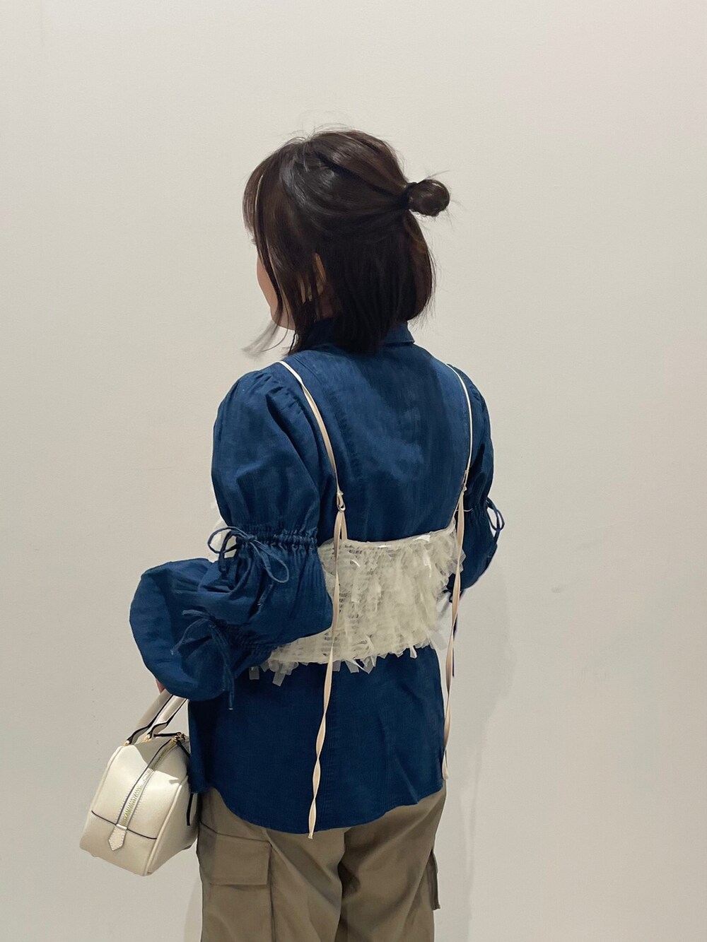 ホワイト系のボストンバッグ、グリーン系のカーゴパンツ、ホワイト系のキャミソールを着用したレディースの春コーディネートの2枚目の写真