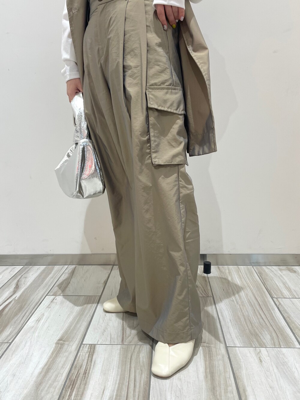 グリーン系のトレンチコート、グリーン系のカーゴパンツ、シルバー系のハンドバッグを着用したレディースの春コーディネートの4枚目の写真