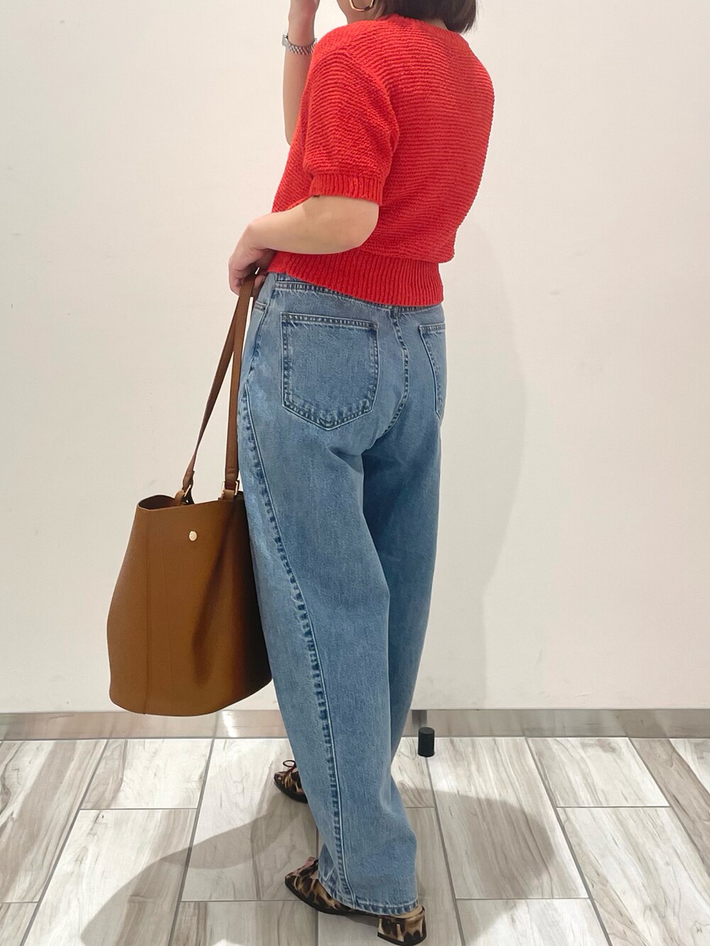 レッド系のニット/セーター、ブルー系のデニムパンツ、イエロー系のトートバッグを着用したレディースの春コーディネートの4枚目の写真