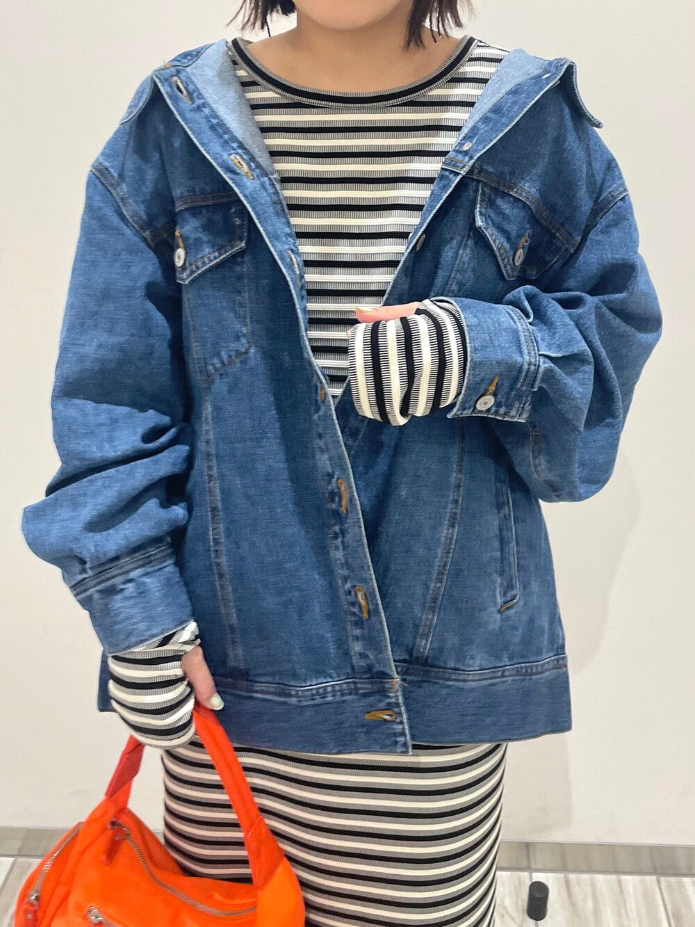 オレンジ系のハンドバッグ、ブラック系のワンピース、ブルー系のデニムジャケットを着用したレディースの春コーディネートの4枚目の写真