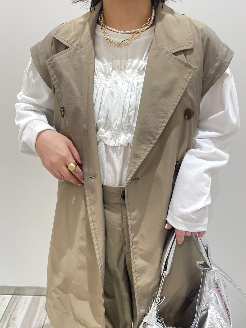 グリーン系のトレンチコート、グリーン系のカーゴパンツ、シルバー系のハンドバッグを着用したレディースの春コーディネートの3枚目の写真