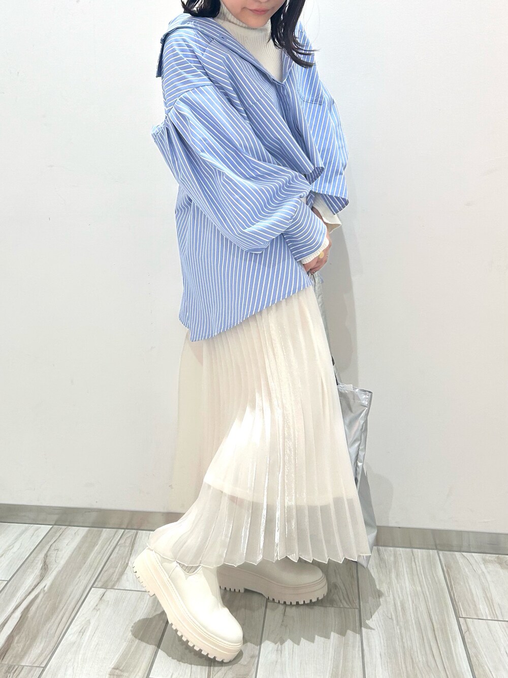 ホワイト系のブーツ、シルバー系のトートバッグ、ホワイト系のスカートを着用したレディースの冬コーディネートの3枚目の写真