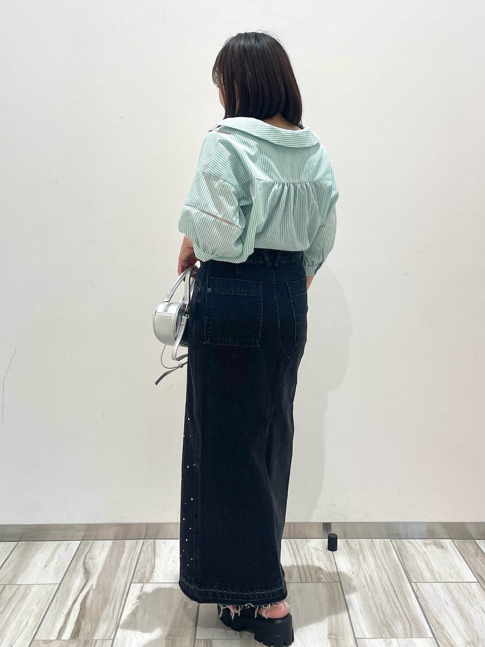 ブラック系のデニムスカートを着用したレディースの夏コーディネートの2枚目の写真