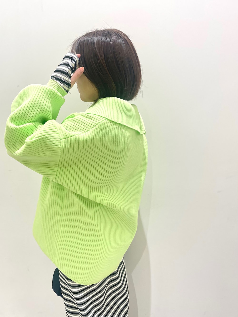 グリーン系のニット/セーター、ブラック系のワンピース、ブルー系のハンドバッグを着用したレディースの春コーディネートの4枚目の写真