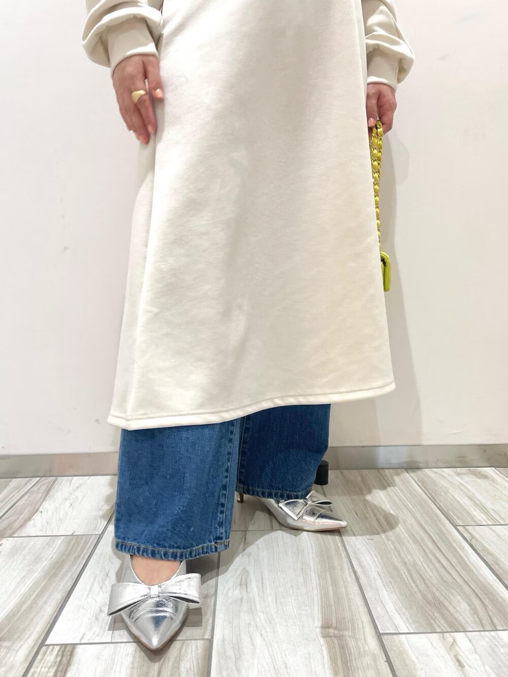 ホワイト系のワンピース、ブルー系のデニムパンツ、イエロー系のショルダーバッグを着用したレディースの冬コーディネートの4枚目の写真