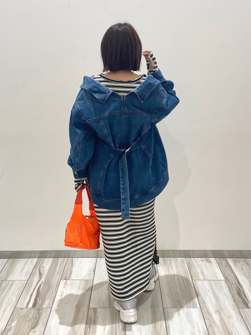 オレンジ系のハンドバッグ、ブラック系のワンピース、ブルー系のデニムジャケットを着用したレディースの春コーディネートの3枚目の写真