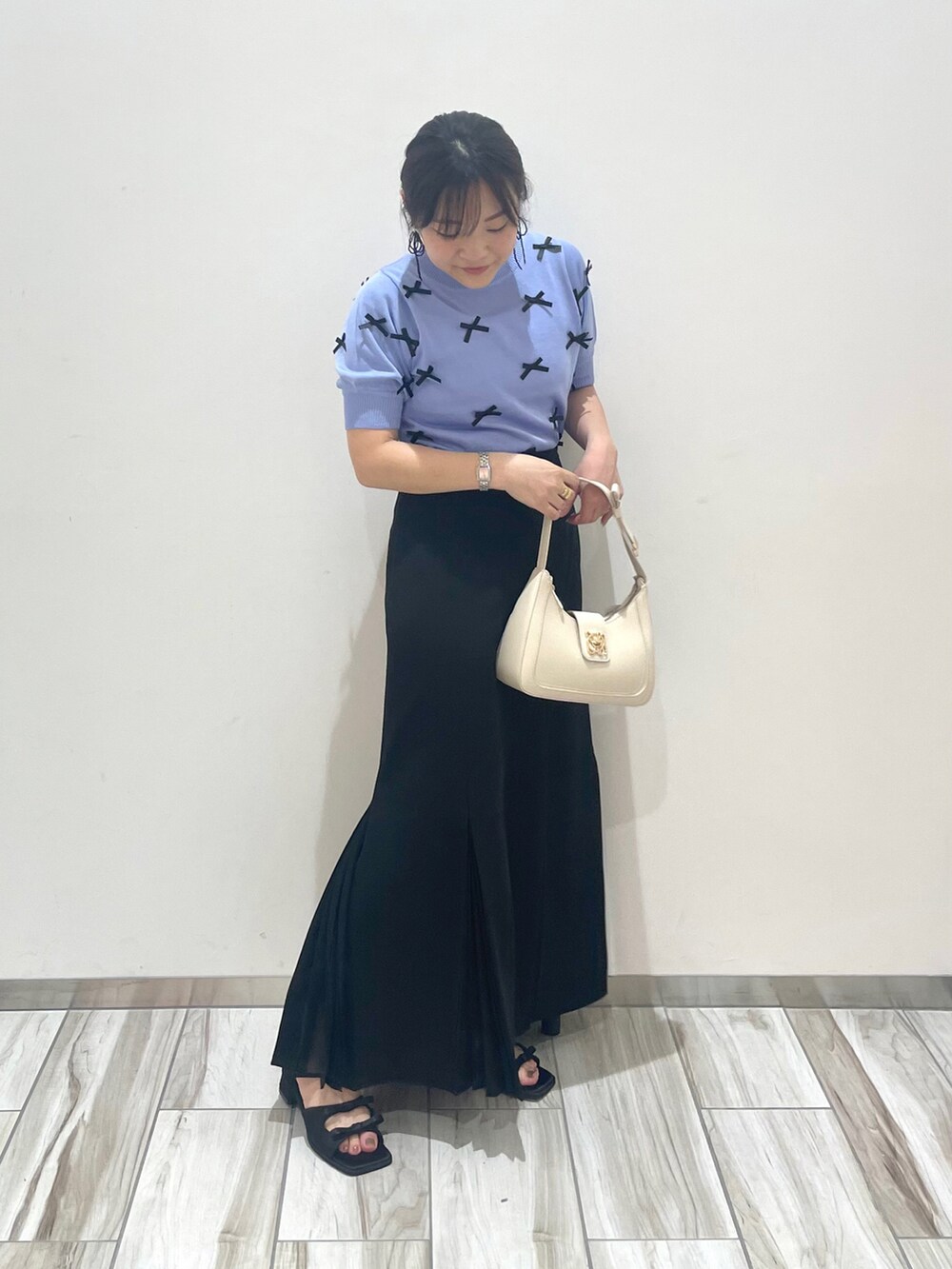 ブルー系のニット/セーター、ホワイト系のハンドバッグを着用したレディースの春コーディネートの2枚目の写真