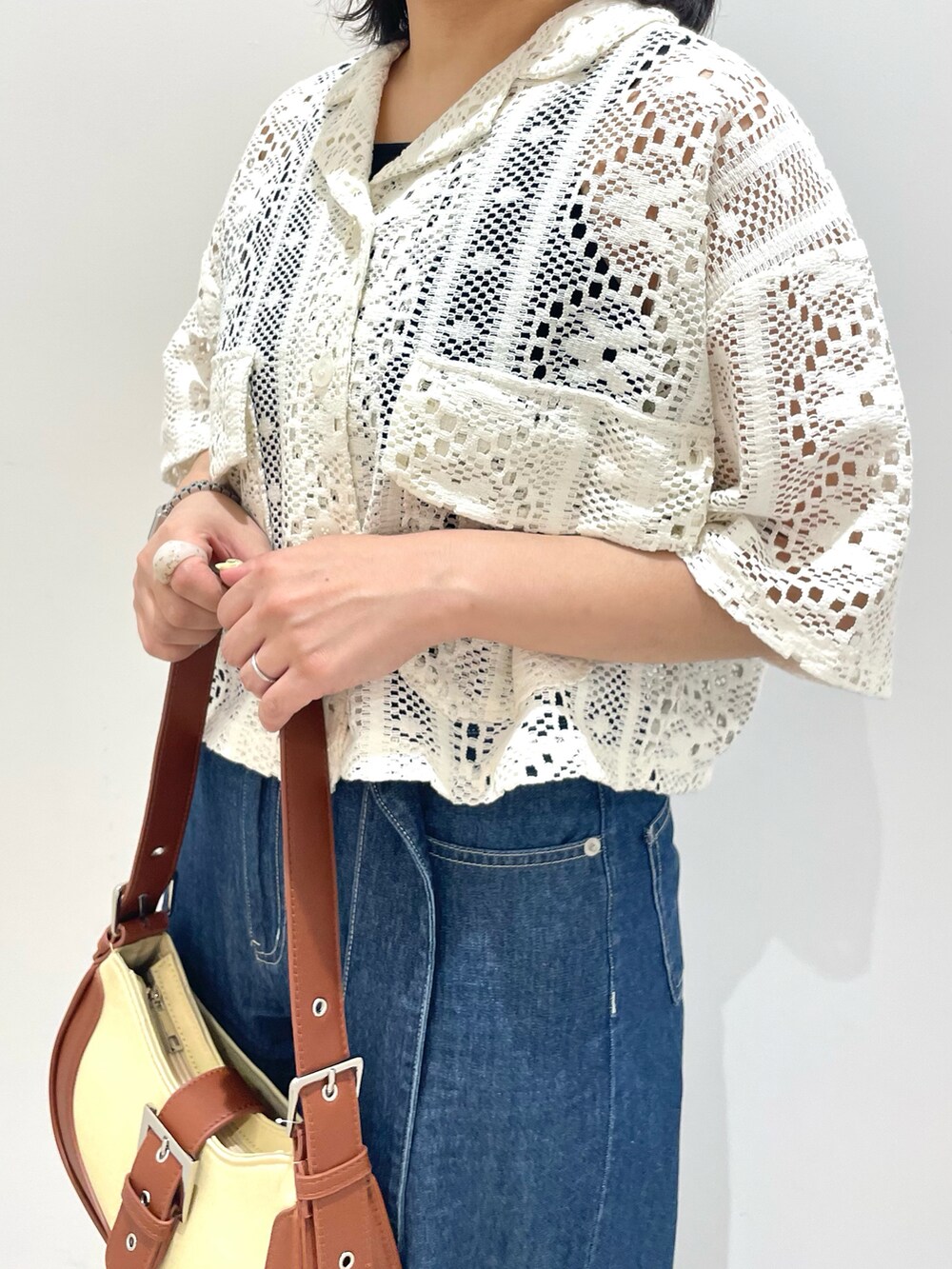 ブルー系のデニムパンツ、ブラウン系のショルダーバッグ、ホワイト系のカーディガン/ボレロを着用したレディースの春コーディネートの2枚目の写真