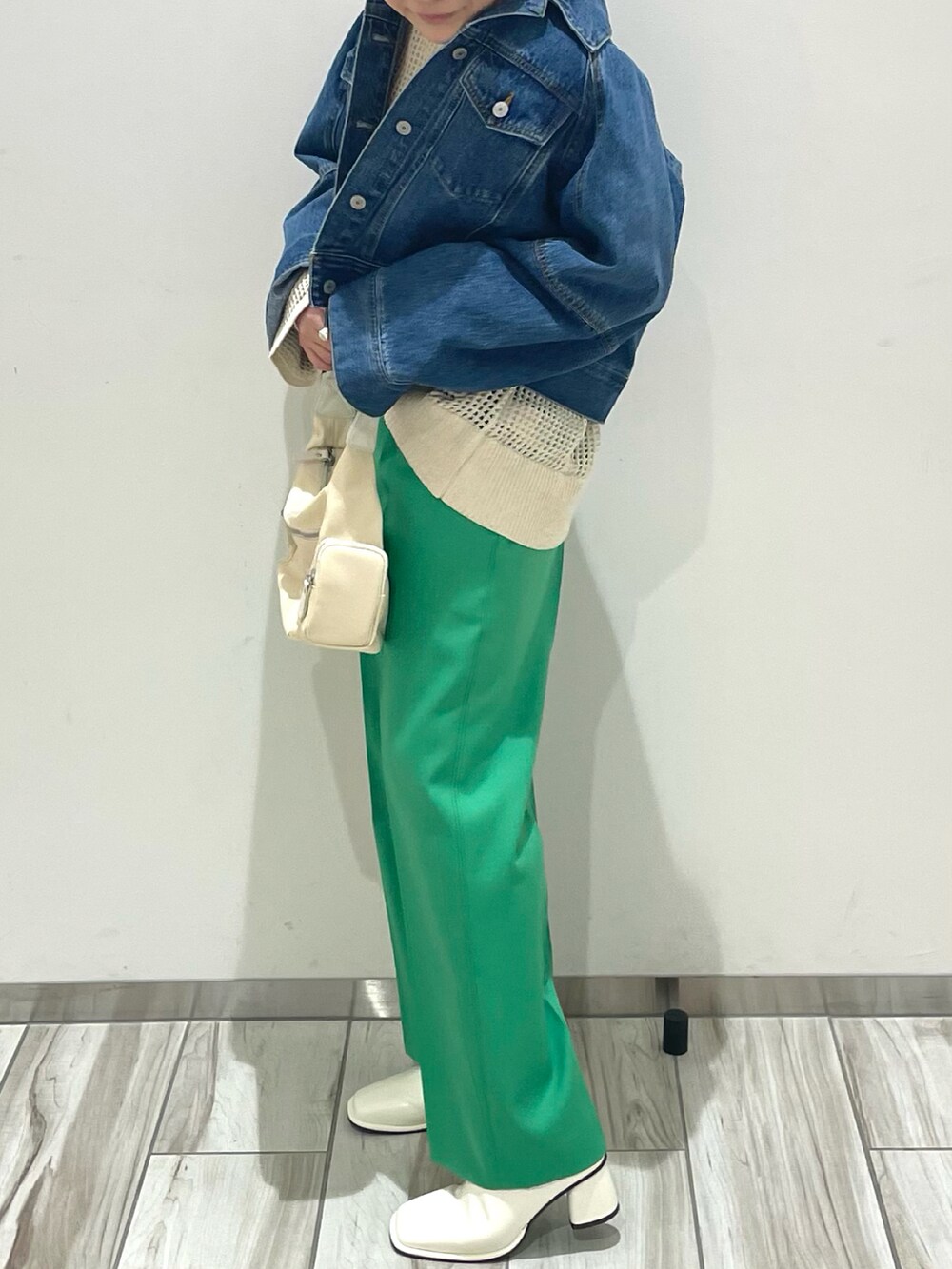 シルバー系のショルダーバッグ、グリーン系のスラックス、ホワイト系のニット/セーターを着用したレディースの春コーディネートの3枚目の写真