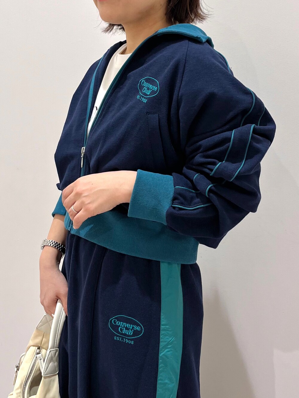 ブルー系のブルゾン、ブルー系のスカート、ホワイト系のハンドバッグを着用したレディースの冬コーディネートの3枚目の写真