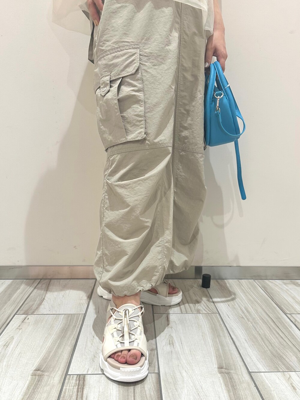 ベージュ系のスカート、ホワイト系のTシャツ/カットソー、ブルー系のショルダーバッグを着用したレディースの春コーディネートの3枚目の写真