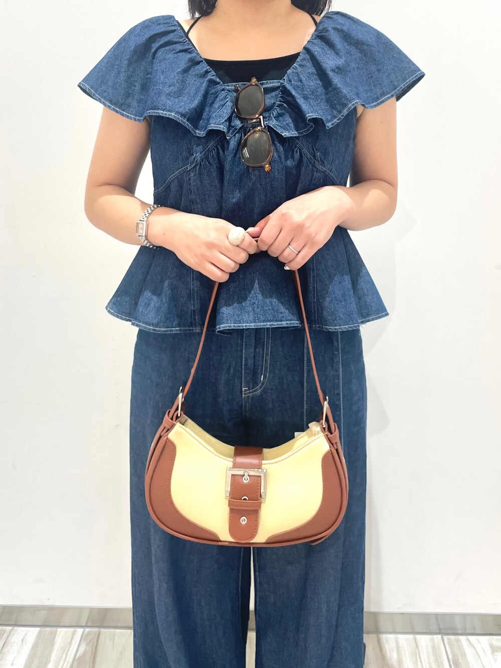 ブルー系のシャツ/ブラウス、ブルー系のデニムパンツ、ブラウン系のショルダーバッグを着用したレディースの春コーディネートの2枚目の写真