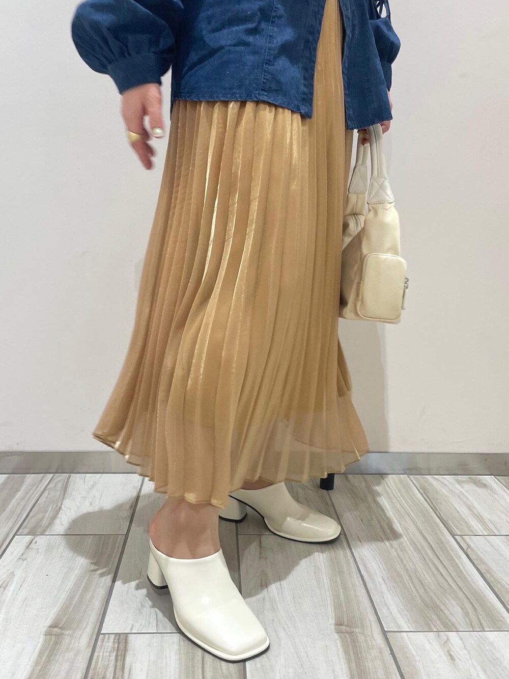 ホワイト系のハンドバッグ、ブルー系のシャツ/ブラウス、ゴールド系のスカートを着用したレディースの春コーディネートの4枚目の写真