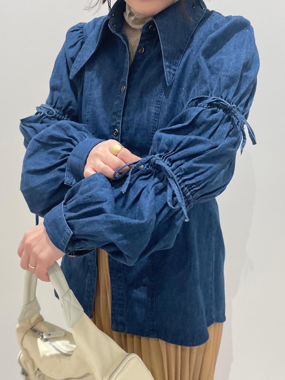 ホワイト系のハンドバッグ、ブルー系のシャツ/ブラウス、ゴールド系のスカートを着用したレディースの春コーディネートの3枚目の写真