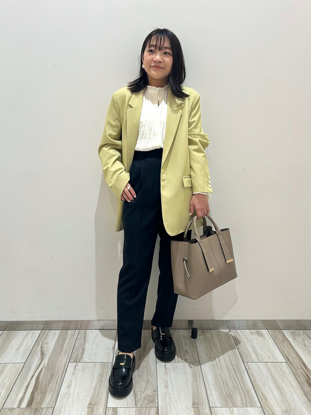 グリーン系のテーラードジャケット、ブルー系のスラックスを着用したレディースの冬コーディネートの2枚目の写真