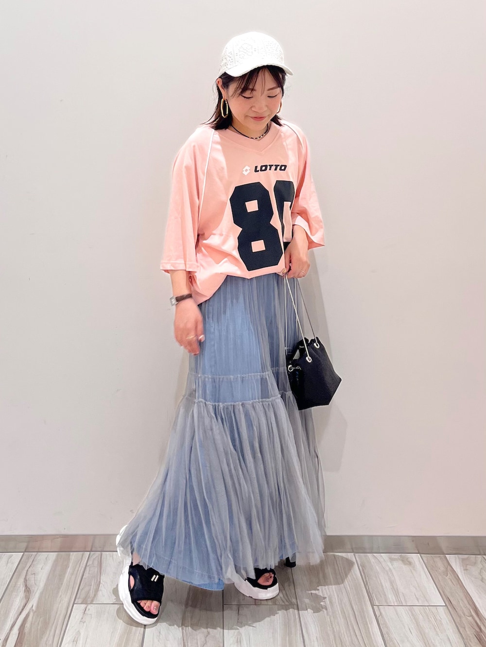 ブラック系のショルダーバッグ、グレー系のスカート、ブルー系のデニムパンツを着用したレディースの夏コーディネートの2枚目の写真