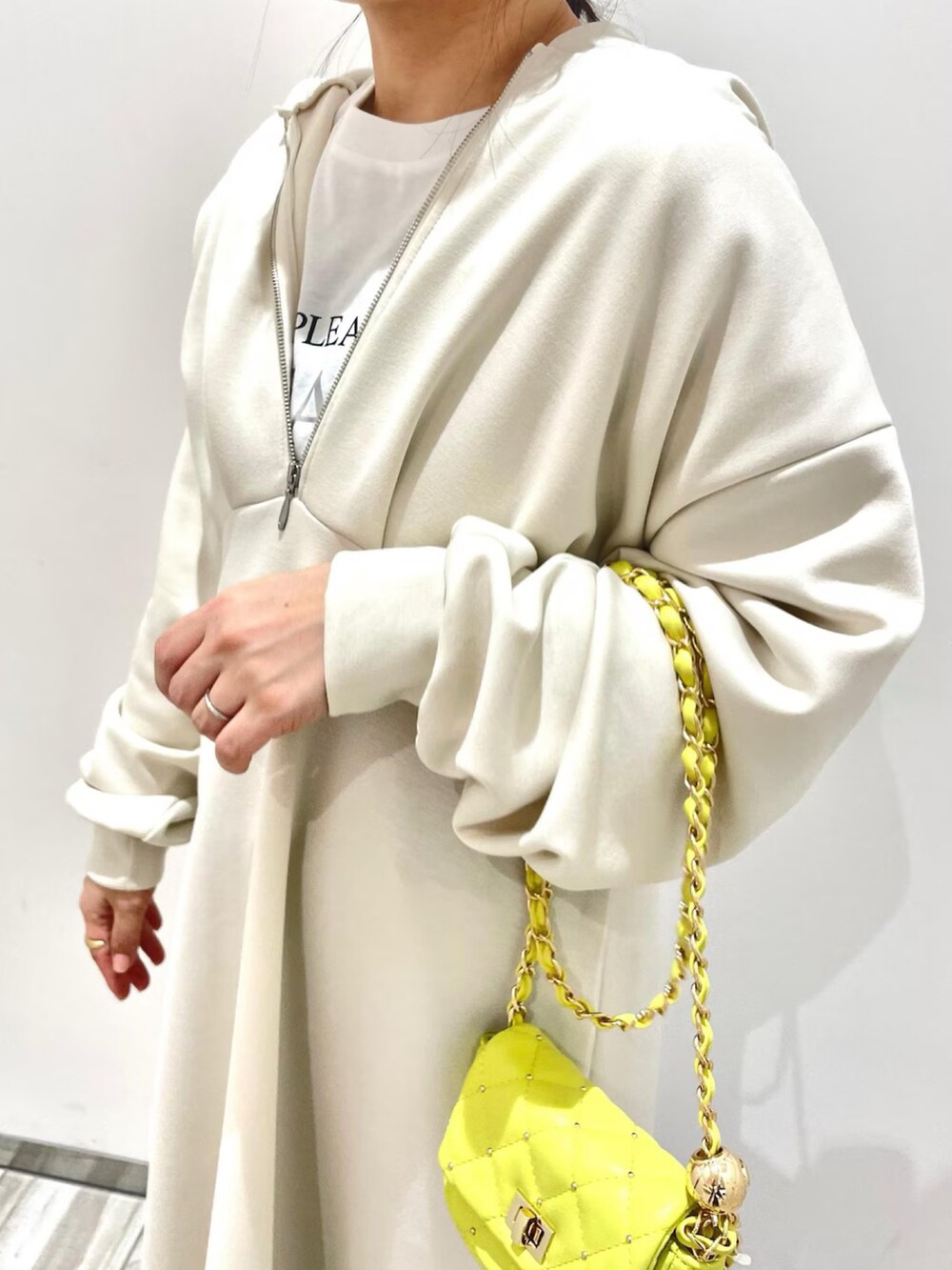 ホワイト系のワンピース、ブルー系のデニムパンツ、イエロー系のショルダーバッグを着用したレディースの冬コーディネートの2枚目の写真