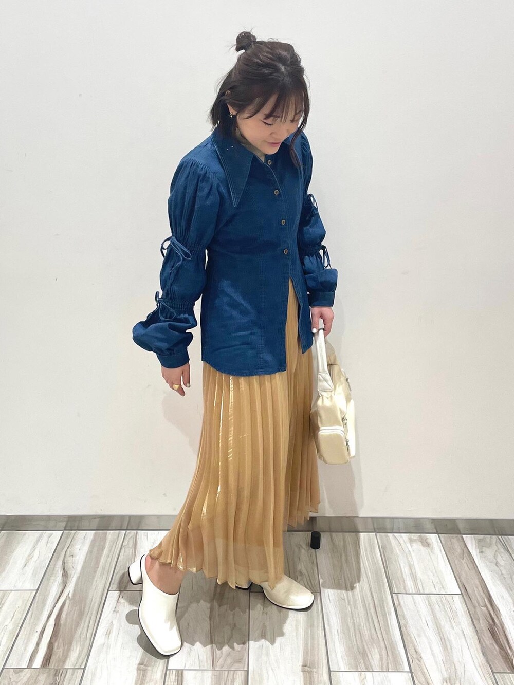 ホワイト系のハンドバッグ、ブルー系のシャツ/ブラウス、ゴールド系のスカートを着用したレディースの春コーディネートの2枚目の写真