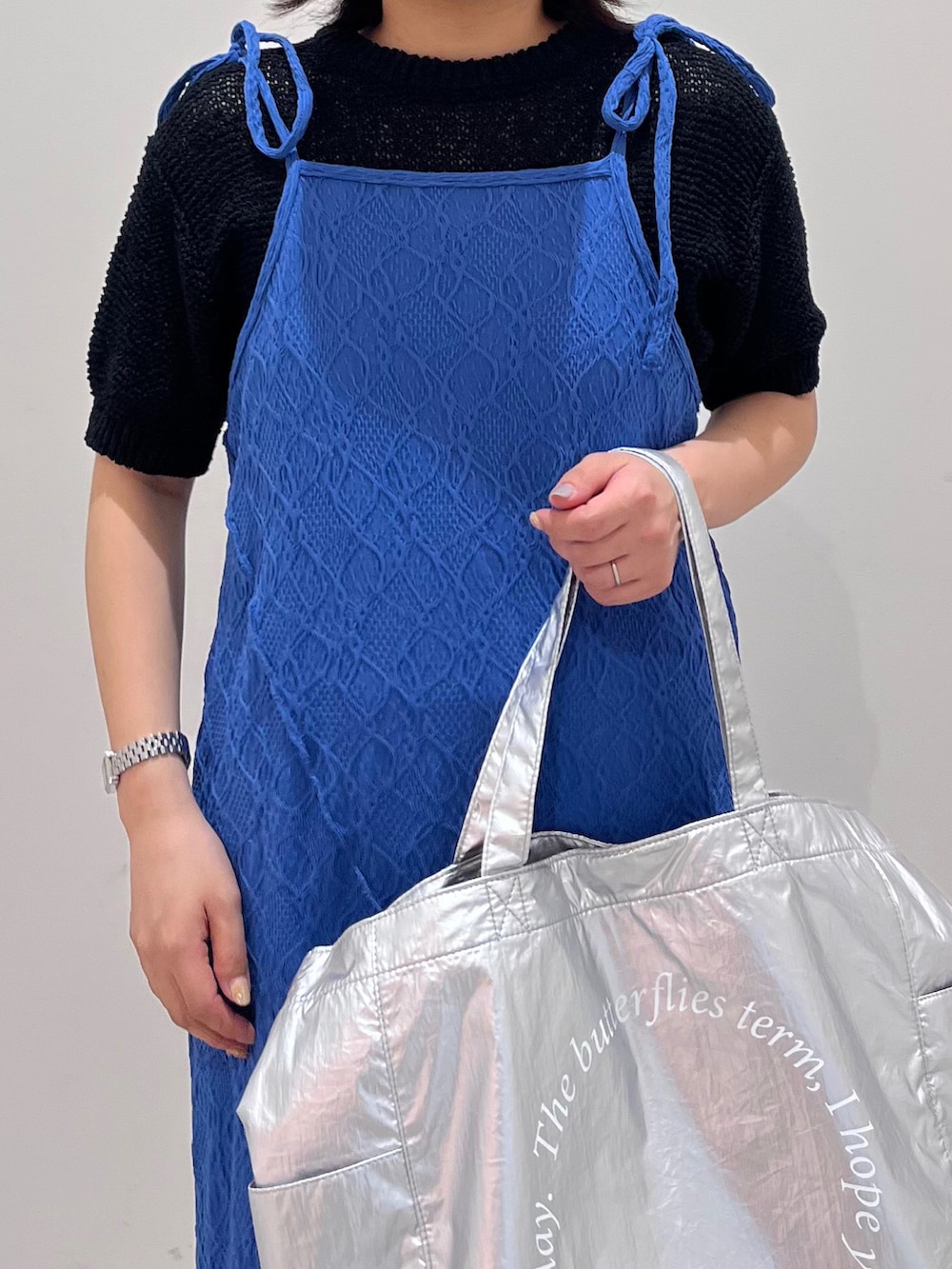 ブルー系のワンピース、シルバー系のトートバッグ、ブラック系のニット/セーターを着用したレディースの春コーディネートの2枚目の写真