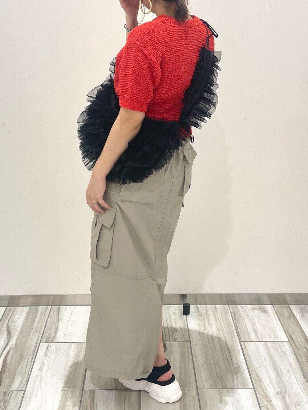 レッド系のニット/セーター、ブラック系のショルダーバッグを着用したレディースの春コーディネートの5枚目の写真