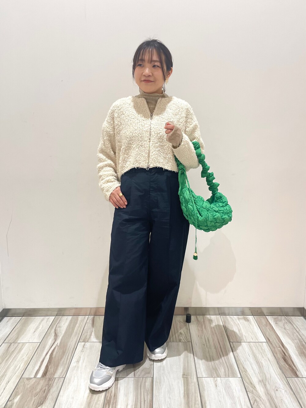 グリーン系のショルダーバッグ、ブルー系のスラックス、ホワイト系のカーディガン/ボレロを着用したレディースの冬コーディネートの2枚目の写真
