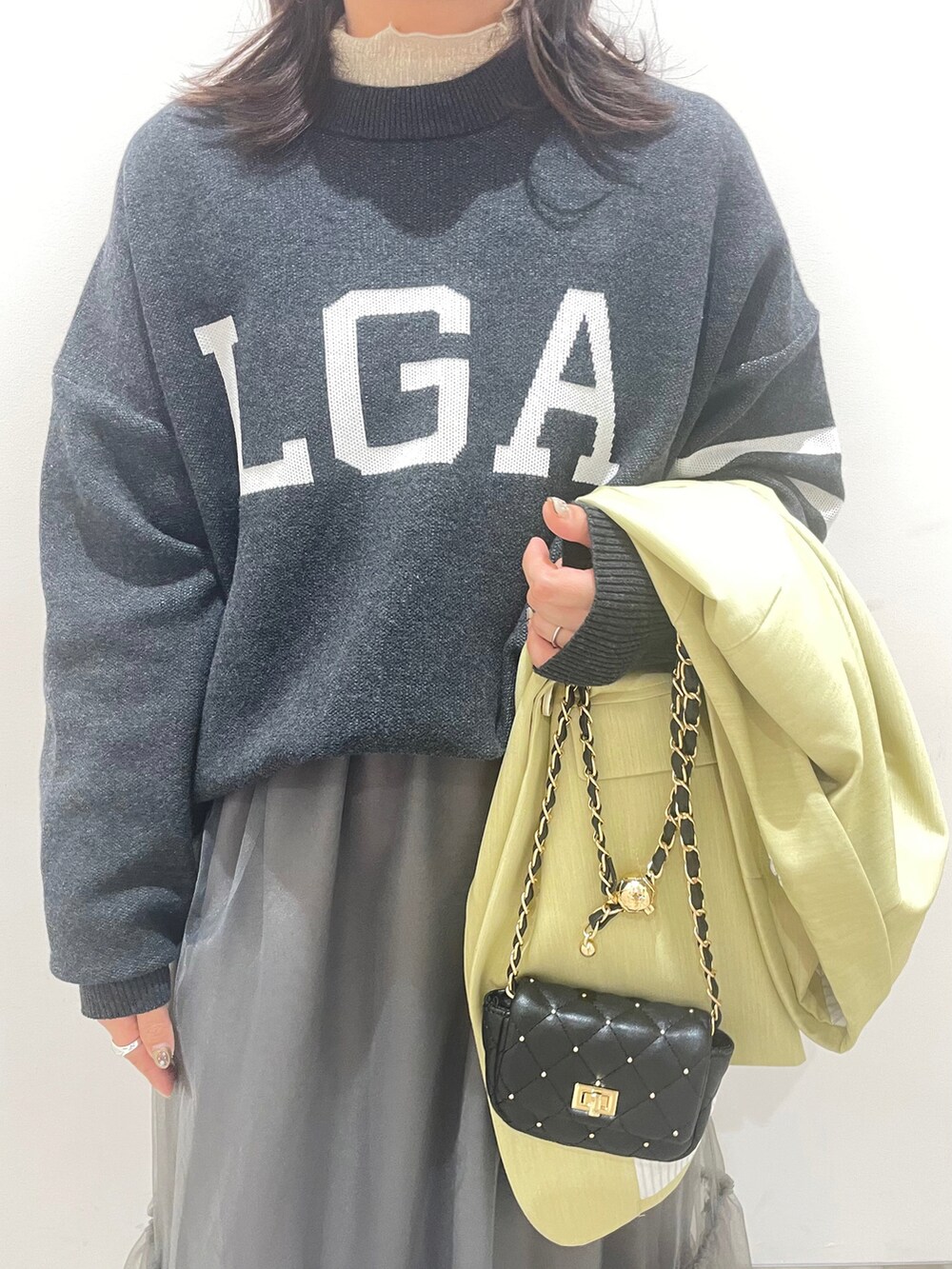 グレー系のスカート、ブラック系のニット/セーターを着用したレディースの冬コーディネートの2枚目の写真