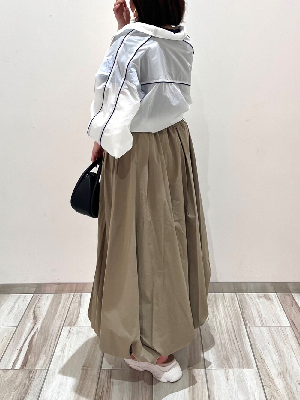 ホワイト系のブルゾン、グリーン系のスカート、ブラック系のショルダーバッグを着用したレディースの春コーディネートの4枚目の写真