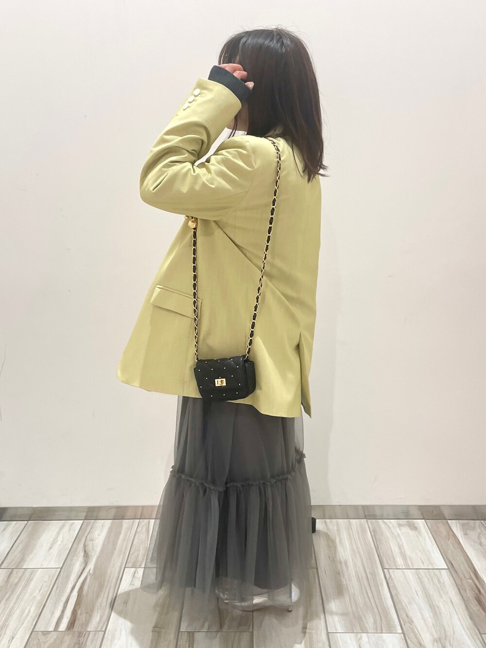 グレー系のスカート、グリーン系のテーラードジャケット、ブラック系のニット/セーターを着用したレディースの冬コーディネートの3枚目の写真