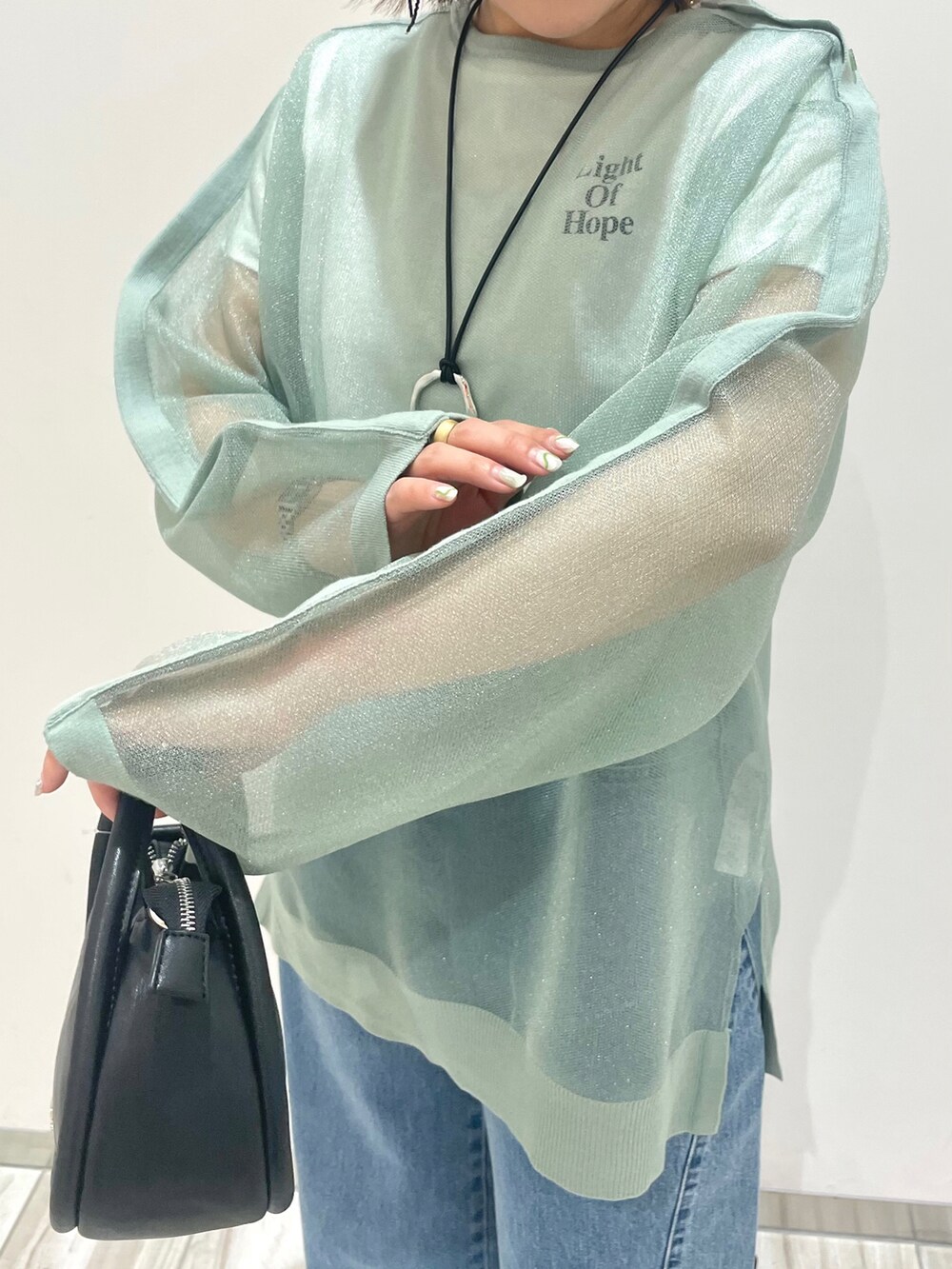 グリーン系のシャツ/ブラウス、ホワイト系のTシャツ/カットソー、ブルー系のデニムパンツを着用したレディースの春コーディネートの3枚目の写真