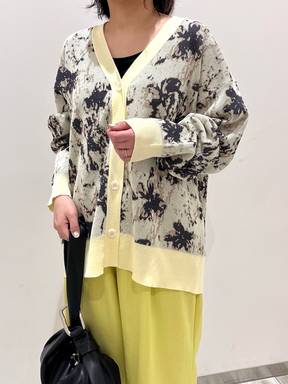 ベージュ系のカーディガン/ボレロ、イエロー系のスラックス、ブラック系のハンドバッグを着用したレディースの春コーディネートの4枚目の写真