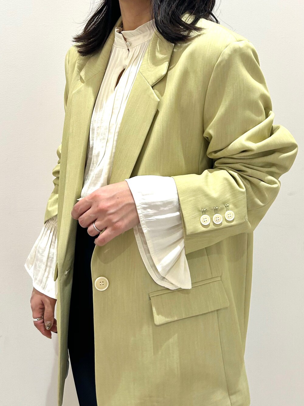 グリーン系のテーラードジャケット、ブルー系のスラックスを着用したレディースの冬コーディネートの3枚目の写真