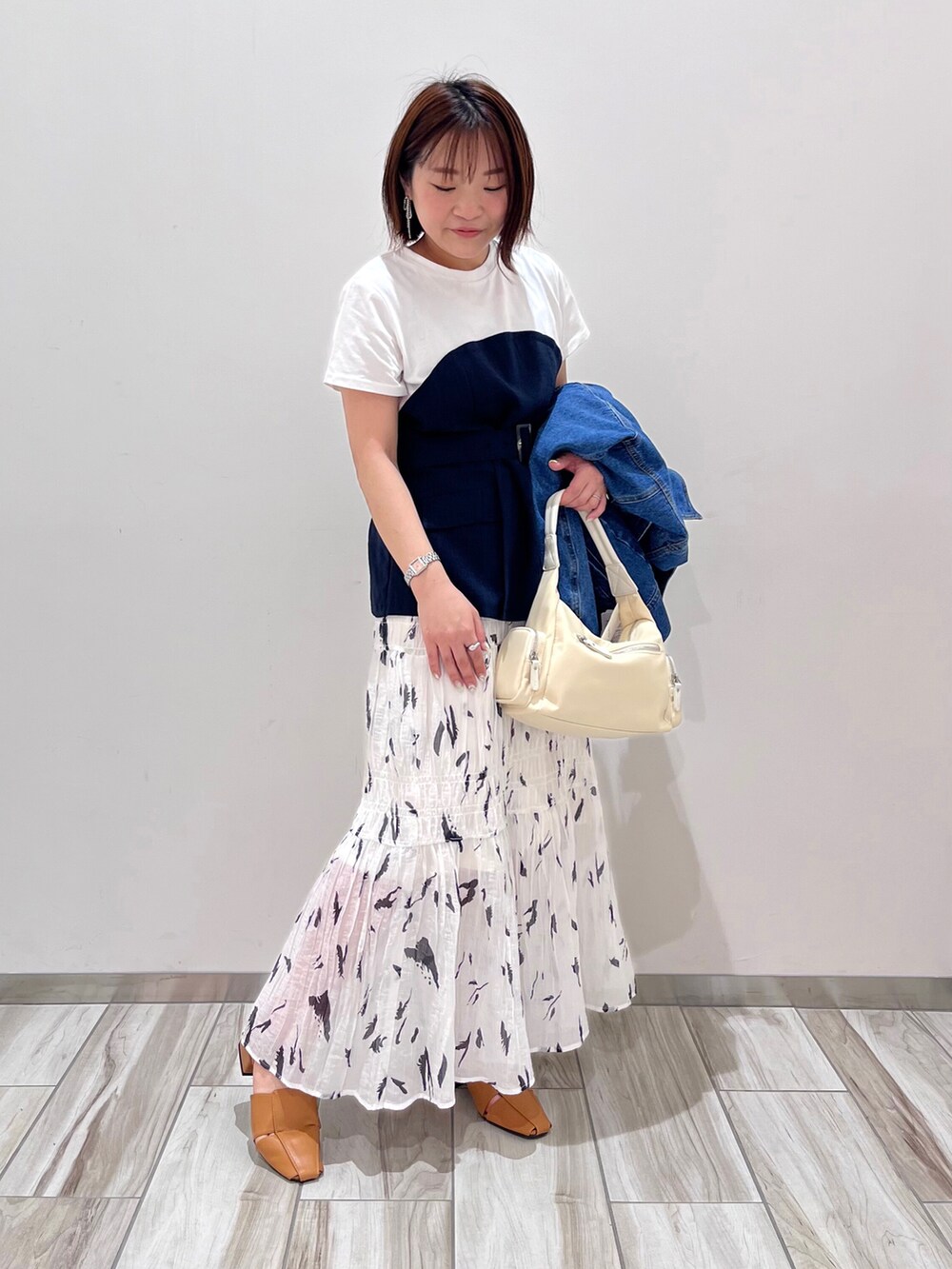 ブルー系のデニムジャケット、ブルー系のTシャツ/カットソー、ホワイト系のスカートを着用したレディースの春コーディネートの4枚目の写真