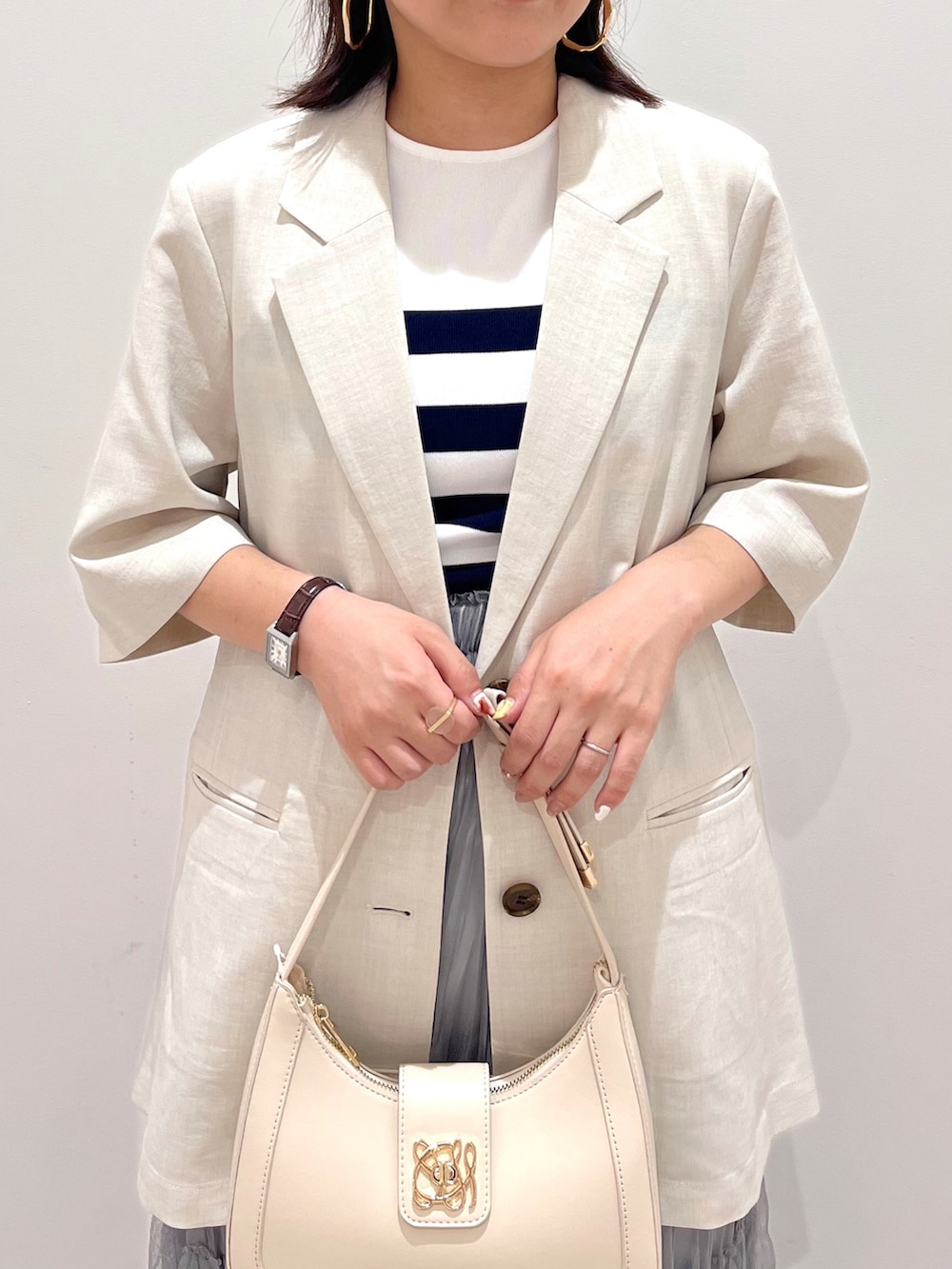 ホワイト系のハンドバッグ、ホワイト系のテーラードジャケット、ホワイト系のニット/セーターを着用したレディースの夏コーディネートの3枚目の写真