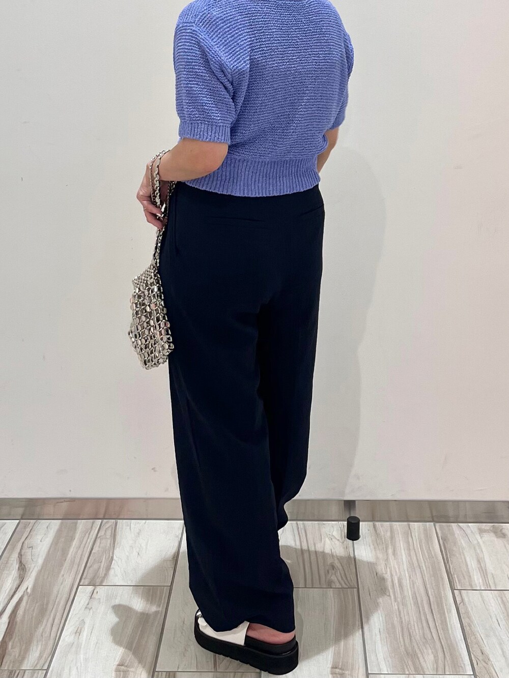 ブルー系のニット/セーター、ブルー系のスラックス、シルバー系のショルダーバッグを着用したレディースの春コーディネートの4枚目の写真