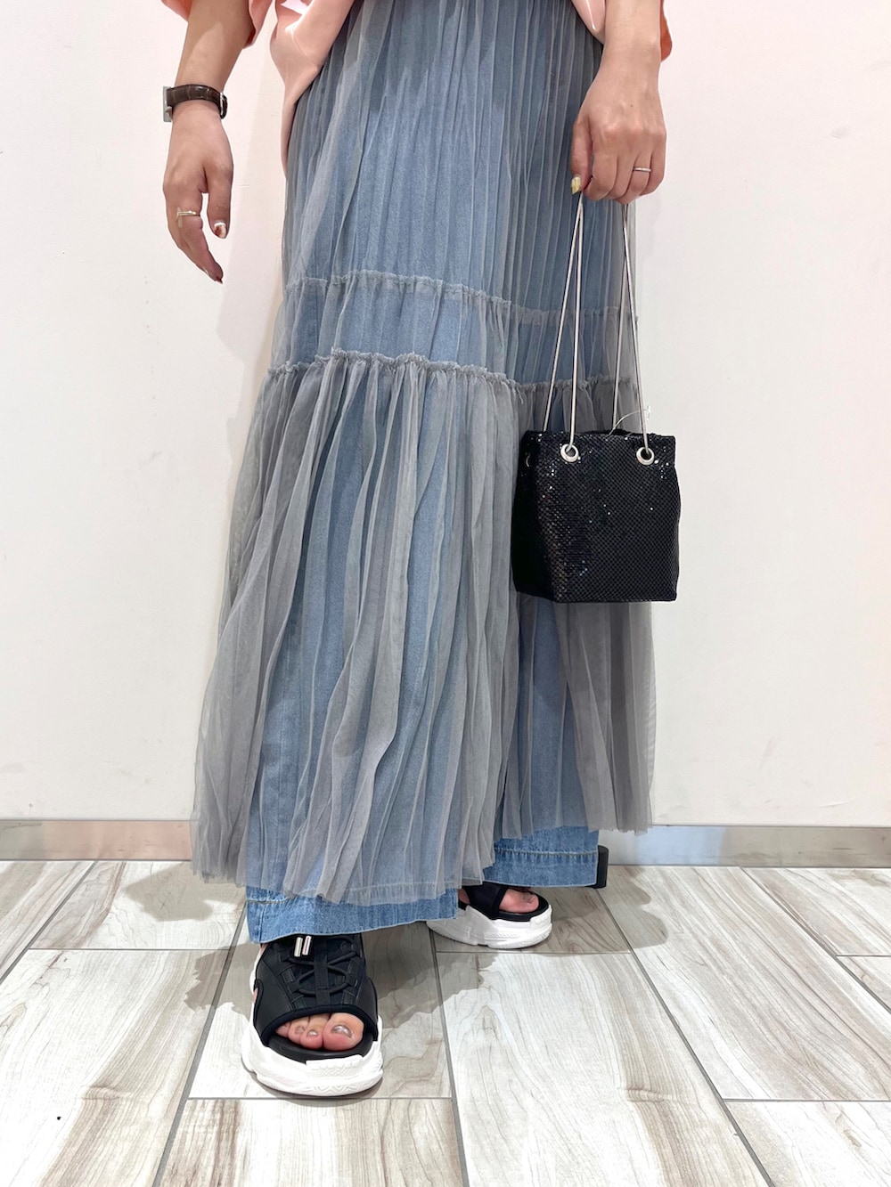 ブラック系のショルダーバッグ、グレー系のスカート、ブルー系のデニムパンツを着用したレディースの夏コーディネートの4枚目の写真