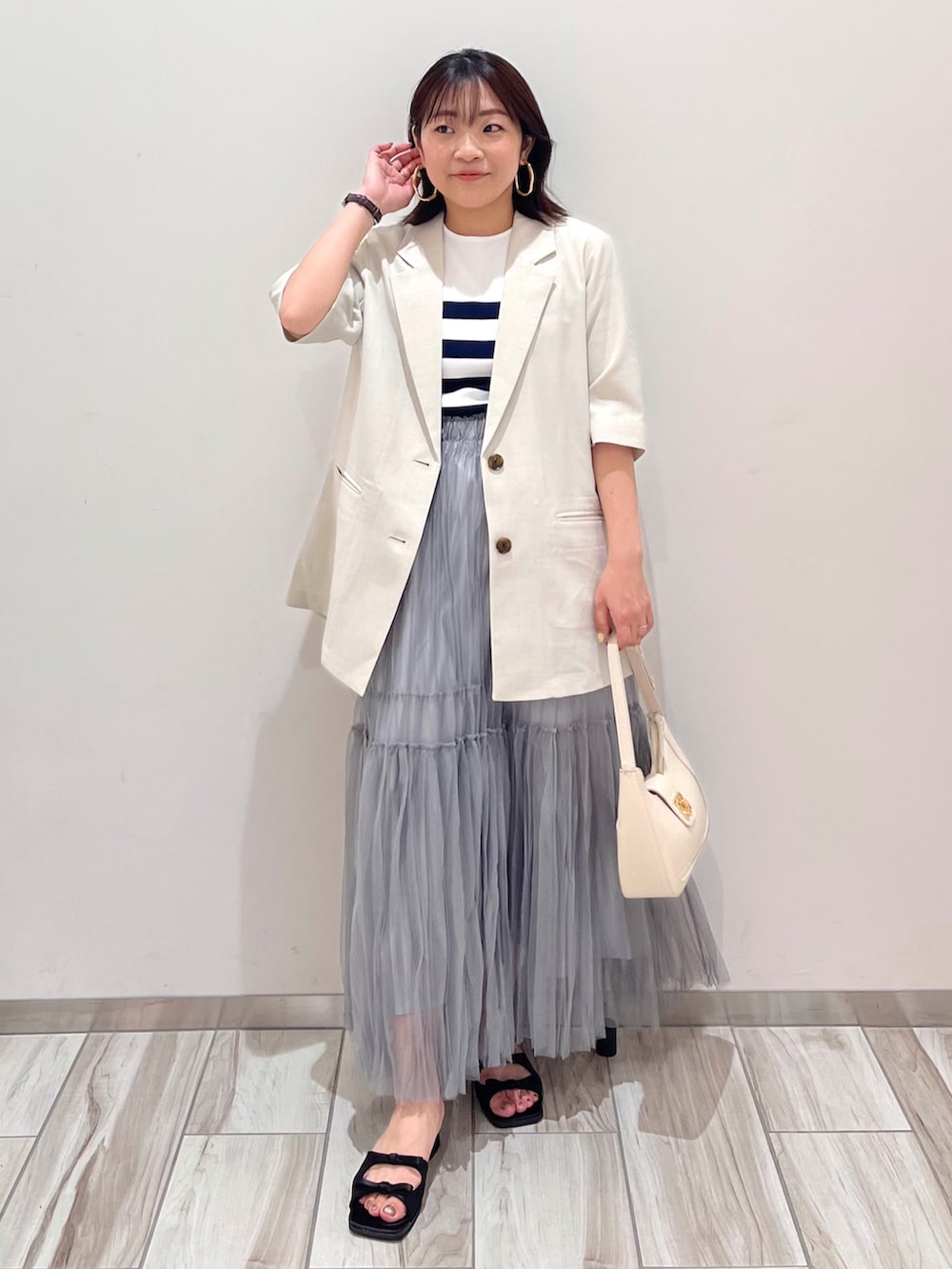 ホワイト系のハンドバッグ、ホワイト系のテーラードジャケット、ホワイト系のニット/セーターを着用したレディースの夏コーディネートの2枚目の写真